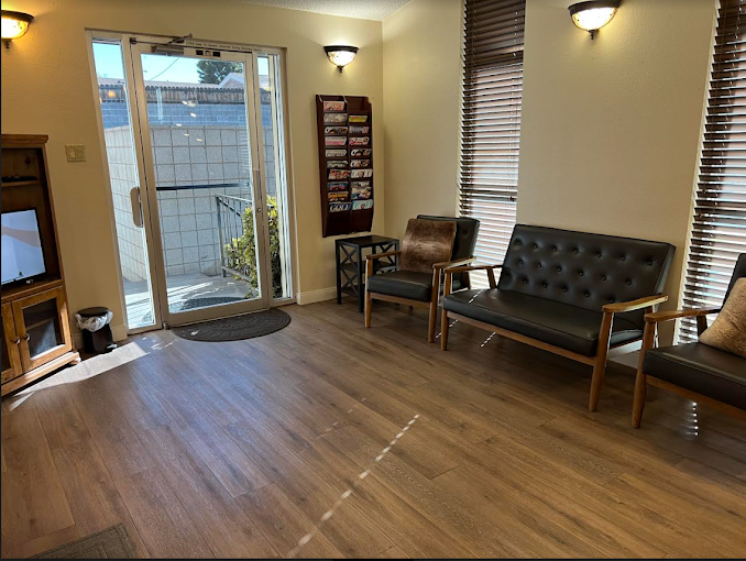 The image shows a modern dental clinic interior with various pieces of equipment, including a dental chair and an X-ray machine.